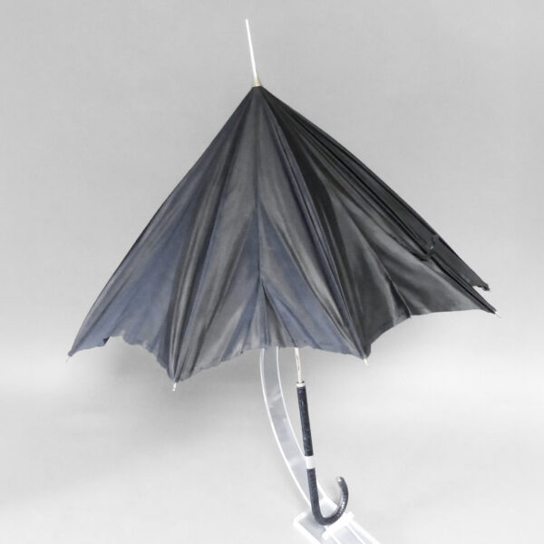 Umbrella with black nylon twill cover, frame with 10 ribs and gilded brass needles, closing tab, originally gilded rod, black crocodile skin handle-butt decorated with a large silver ring.